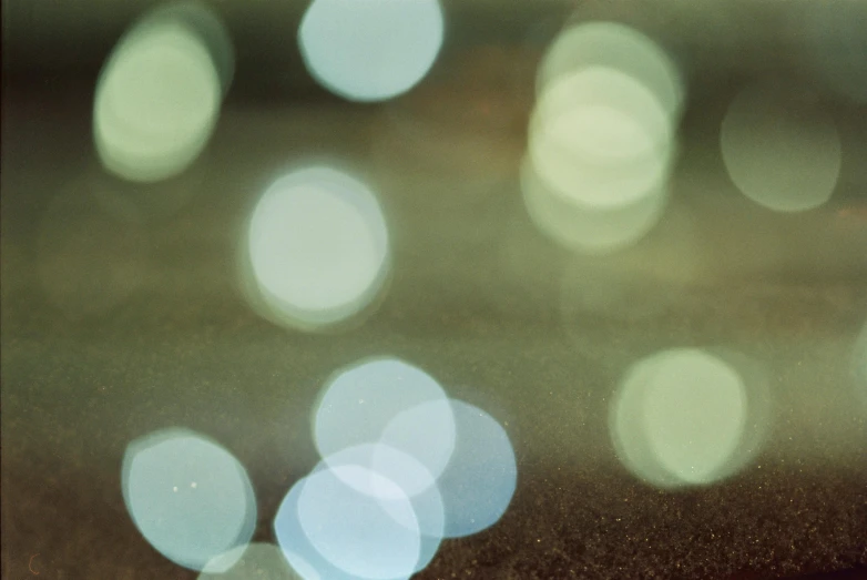 a close up of a cell phone on a table, a picture, inspired by Elsa Bleda, tonalism, light circles, green sparkles, 1960s color photograph, hasselblad film bokeh