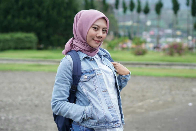 a woman wearing a denim jacket and a pink hijab, hurufiyya, background image, at college, slight smirk, 9 k