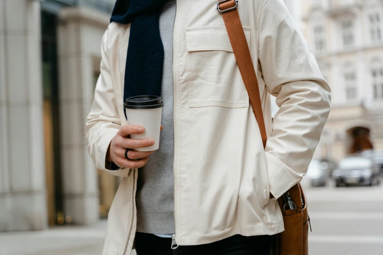 a man standing on a city street with a cell phone in his hand, trending on pexels, trench coat with many pockets, milk and mocha style, cropped shirt with jacket, iced latte