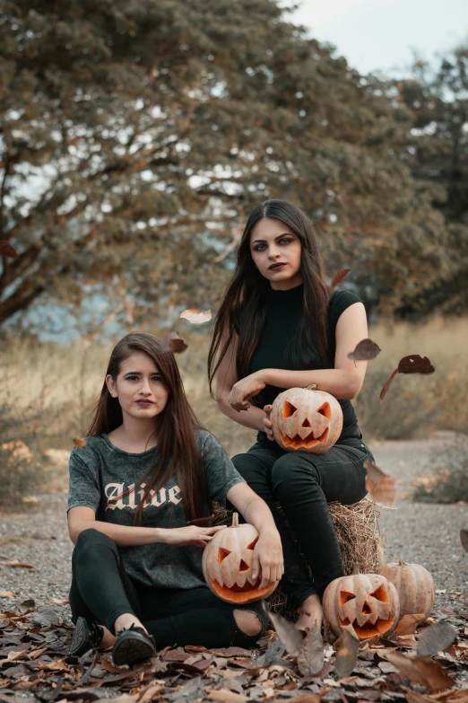 a couple of women sitting on top of a pile of pumpkins, trending on pexels, realism, gothic clothing, wearing a black t-shirt, 2019 trending photo, lookbook