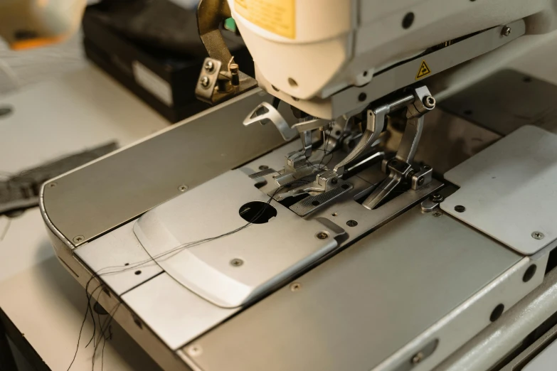 a close up of a sewing machine on a table, a silk screen, inspect in inventory image, ignant, metal garments, thumbnail