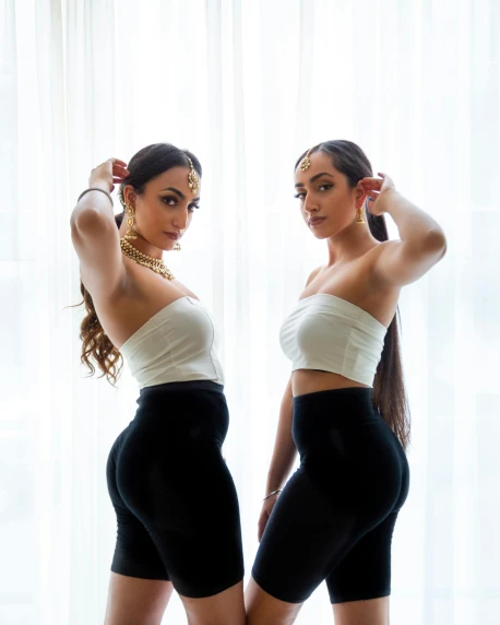 a couple of women standing next to each other, inspired by Wang Duo, unsplash, arabesque, demi rose, ponytails, 3 / 4 pose, twins