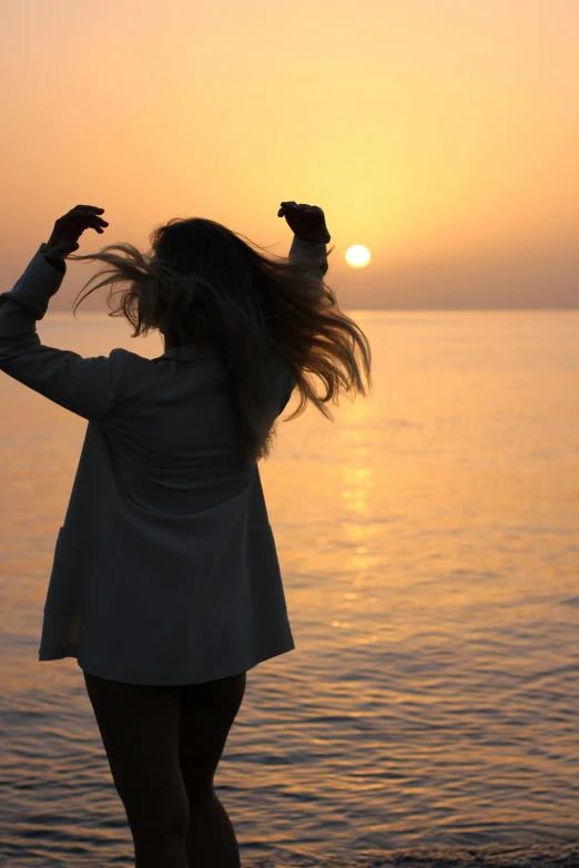 a woman standing on top of a beach next to the ocean, pexels contest winner, romanticism, flowing backlit hair, ((sunset)), doing a sassy pose, profile image