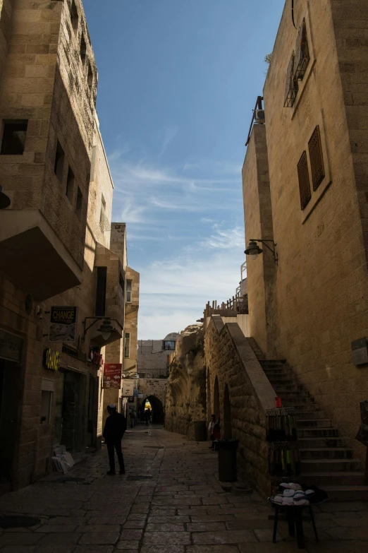 a couple of people walking down a narrow street, les nabis, al - qadim, lower and upper levels, street corner, skies behind