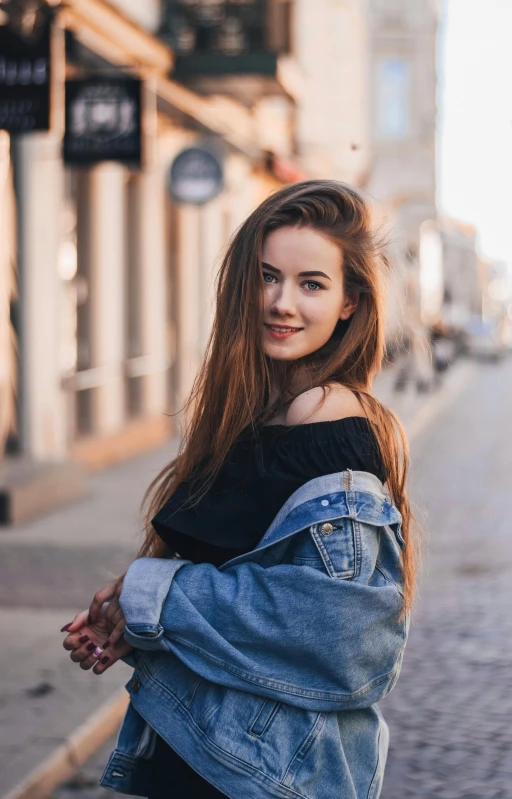 a woman standing on the side of a street, by Adam Marczyński, pexels contest winner, smiling young woman, wearing a jeans jackets, slightly pixelated, long hair girl