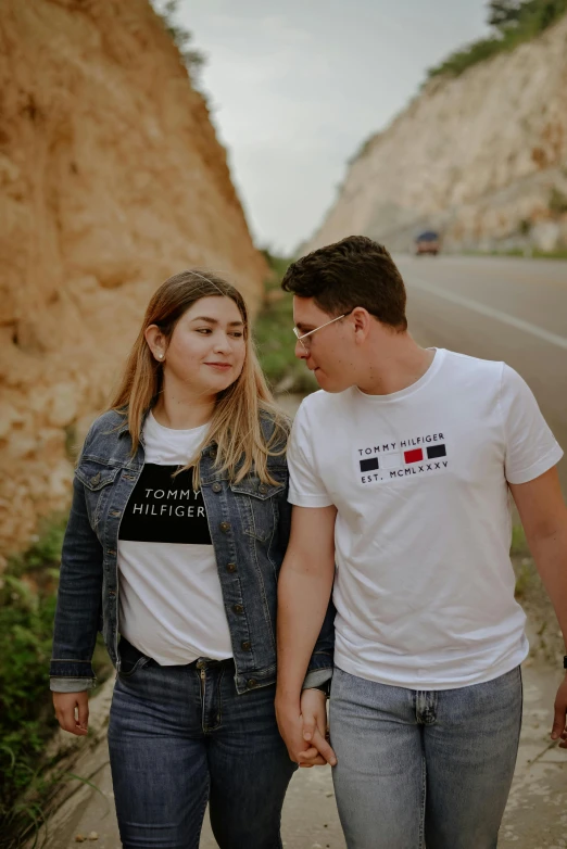 a man and a woman walking down a road, an album cover, by Julia Pishtar, trending on unsplash, t-shirt, monaco, lesbian, conservative