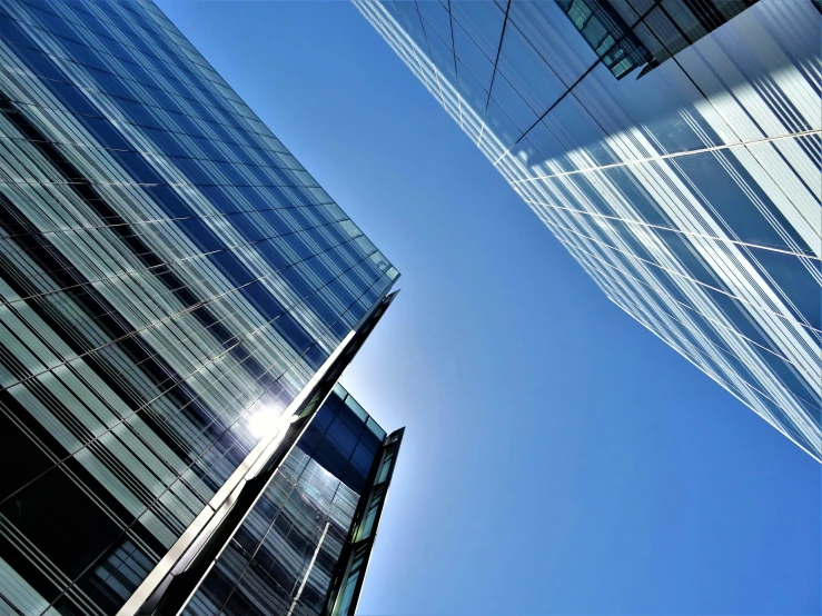 a couple of tall buildings next to each other, inspired by Richard Wilson, pexels contest winner, glass openings, clear blue sky, thumbnail, multiple stories