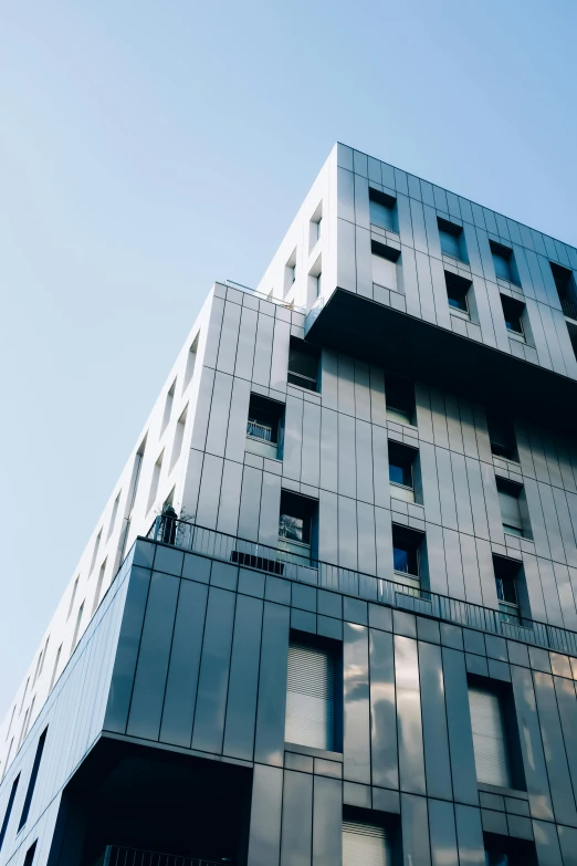 a very tall building with lots of windows, inspired by Bauhaus, unsplash, metal cladding wall, low quality photo, square, long shot from back