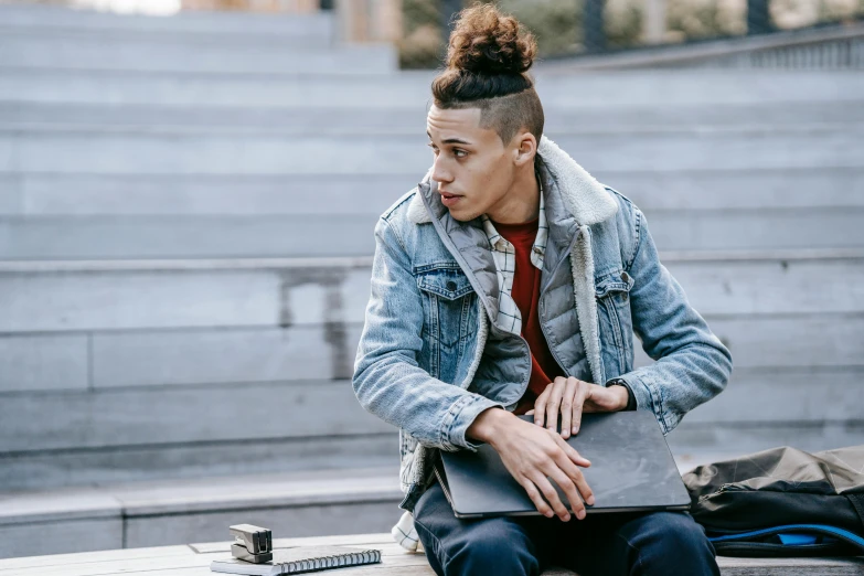 a man sitting on a bench with a laptop, trending on pexels, hair styled in a bun, wearing jacket, male teenager, ashteroth