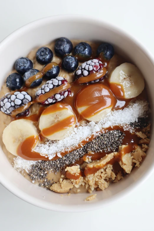 a bowl of oatmeal topped with bananas and blueberries, inspired by Richmond Barthé, trending on pexels, caramel, embedded with gemstones, gif, blonde crea