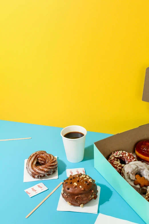 a box of donuts next to a cup of coffee, snacks, thumbnail, dwell, vibrant