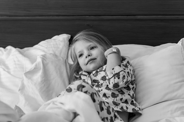 a black and white photo of a little girl laying in bed, by Emma Andijewska, pexels, square, medical, wearing a robe, a plaster on her cheek