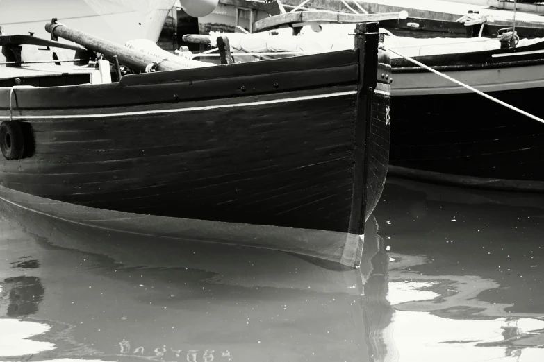 a black and white photo of a boat in the water, a black and white photo, wooden sailboats, low dutch angle, hyperdetailed photograph, moored