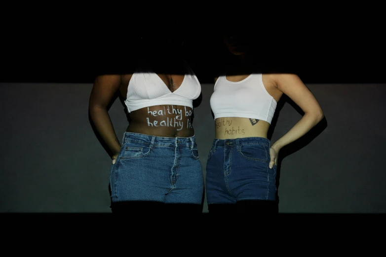 a couple of women standing next to each other, an album cover, inspired by Nan Goldin, trending on pexels, graffiti, physical : tinyest midriff ever, healthcare, on black background, denim