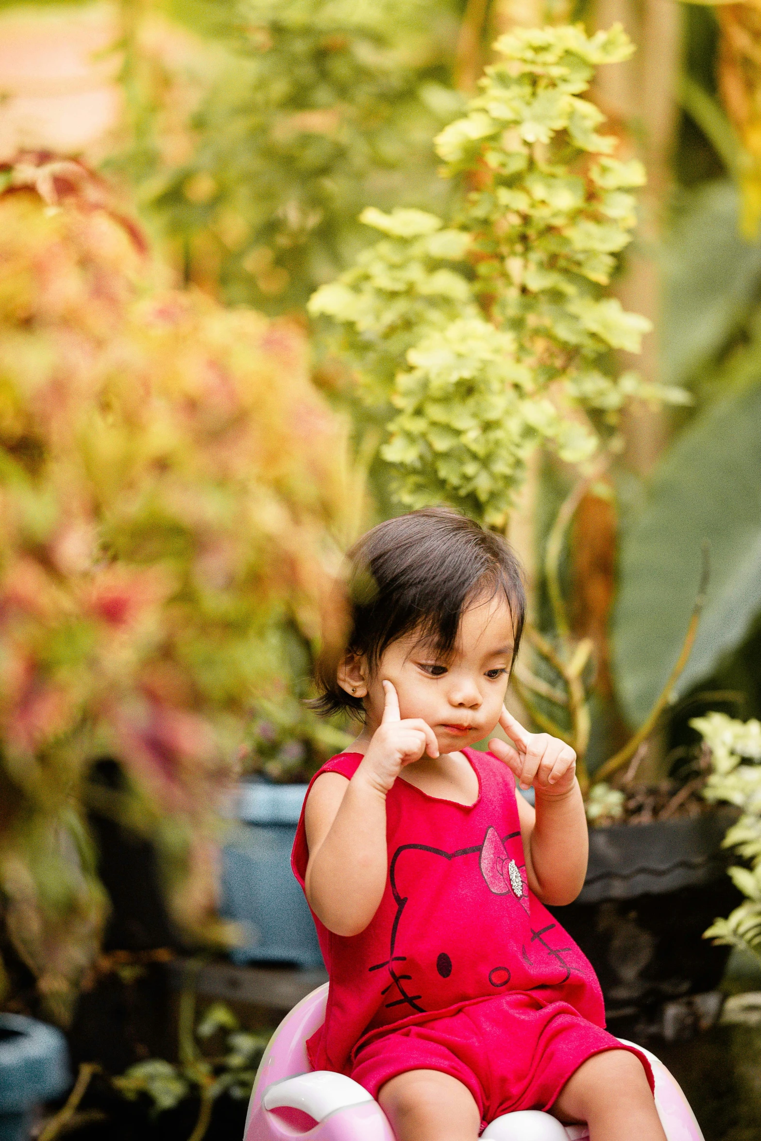 a little girl sitting on top of a potted plant, by Basuki Abdullah, pexels contest winner, hand on his cheek, giving the middle finger, lush garden surroundings, sittin