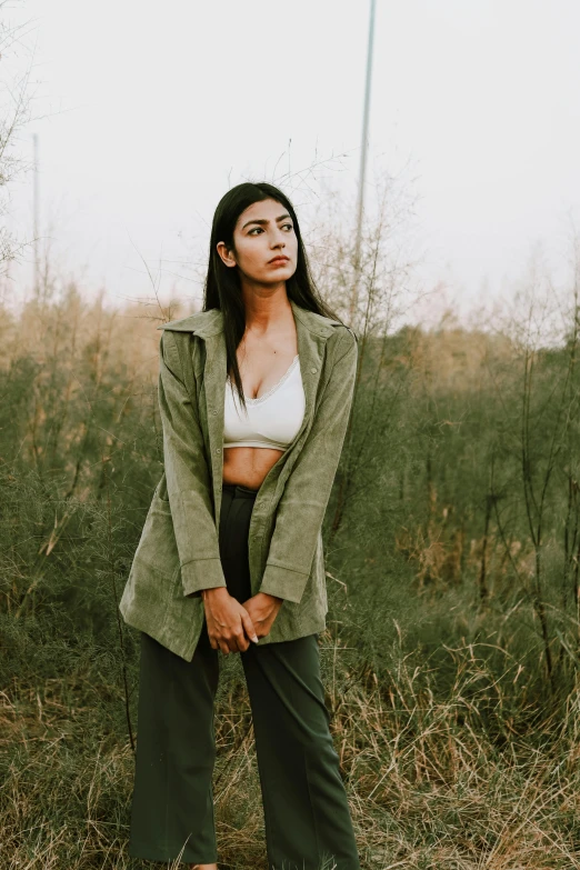 a woman standing in the middle of a field, trending on pexels, cropped shirt with jacket, olive skin color, at a fashion shoot, provocative indian