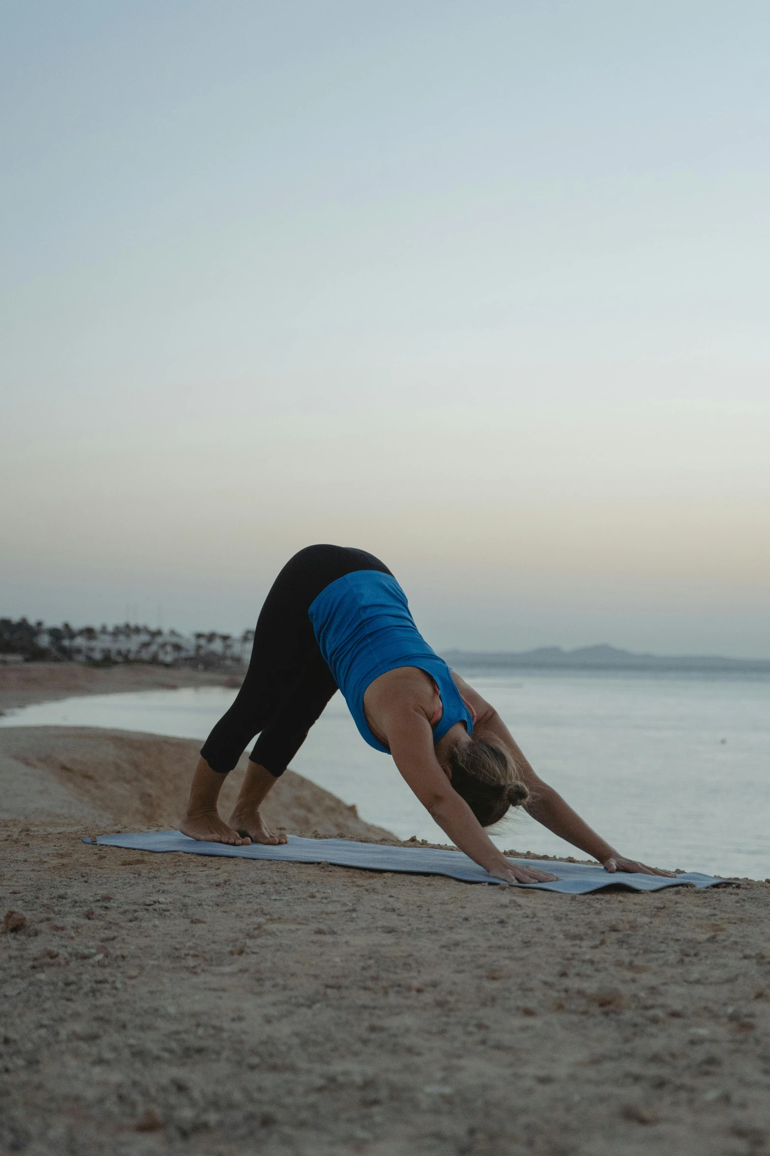 a woman doing a yoga pose on the beach, in egypt, tail fin, shot with sony alpha, evening time