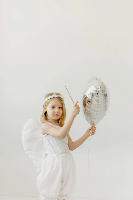 a little girl in a white dress holding a silver balloon, wearing angel halo, foil, full product shot, grey