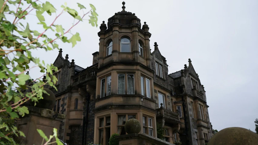 a tall building with a clock on top of it, inspired by Sydney Prior Hall, art nouveau, gothic mansion, grey skies rain, in scotland, as seen from the canopy