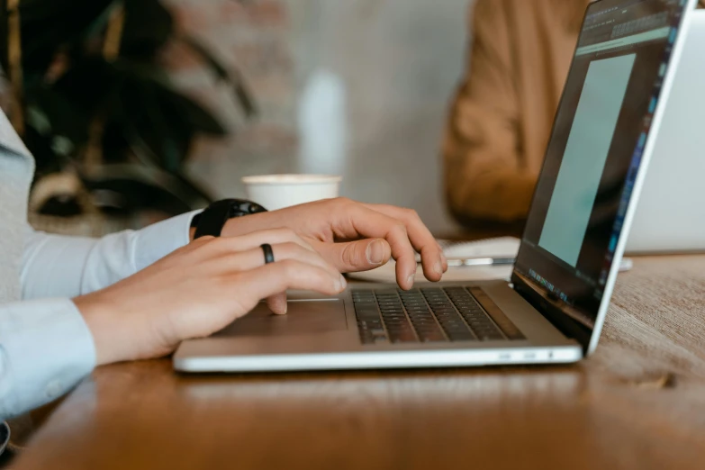 a close up of a person typing on a laptop, by Carey Morris, trending on pexels, realism, brown, background image, people sitting at tables, professional