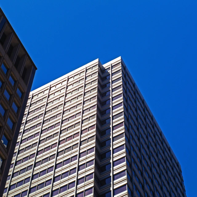 a couple of tall buildings sitting next to each other, a photo, unsplash, brutalism, bright blue sky, brown, square lines, san francisco