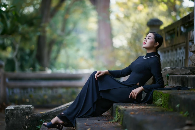 a woman in a black dress sitting on some steps, inspired by Li Di, pexels contest winner, ao dai, 15081959 21121991 01012000 4k, seductive reclining pose, in a park