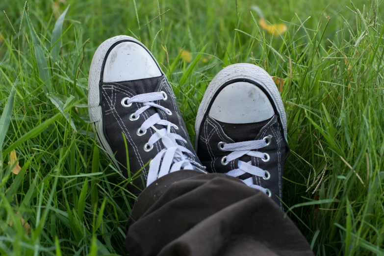 a pair of black sneakers sitting on top of a lush green field, pexels contest winner, wearing casual clothes, worn out clothes, converse, avatar image