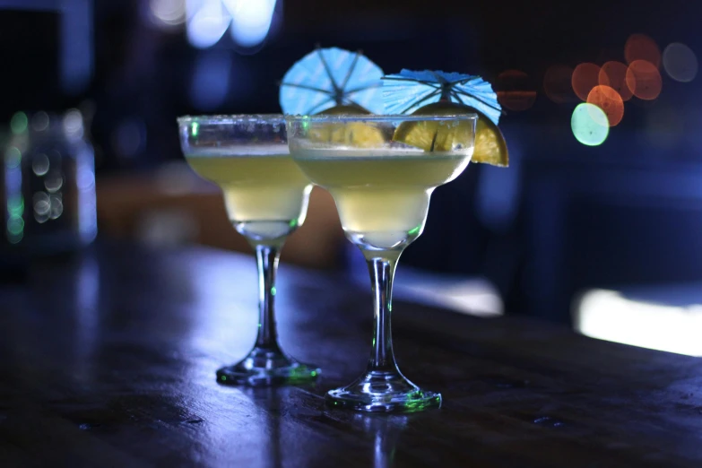 a couple of glasses sitting on top of a wooden table, holding a martini, multiple stories, profile image, chinatown bar