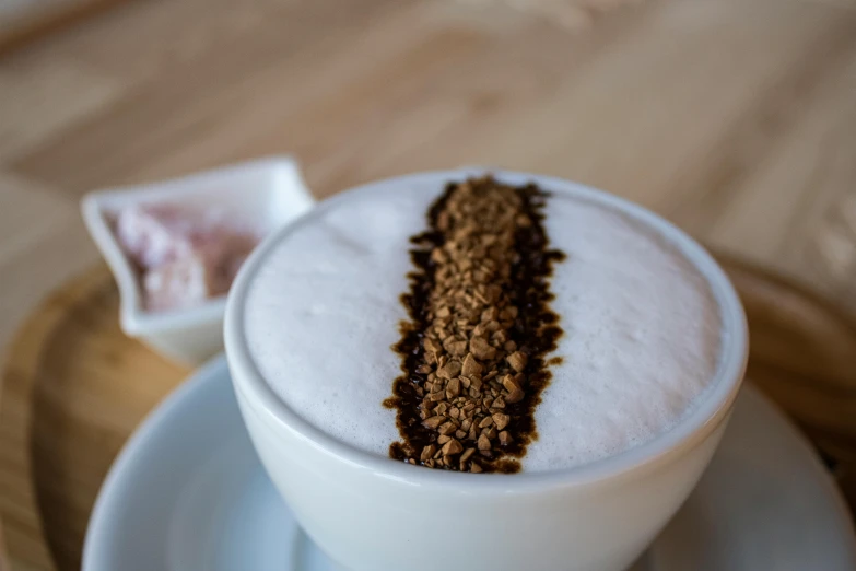 a close up of a cup of coffee on a saucer, bowl filled with food, blended, white foam, sprinkles