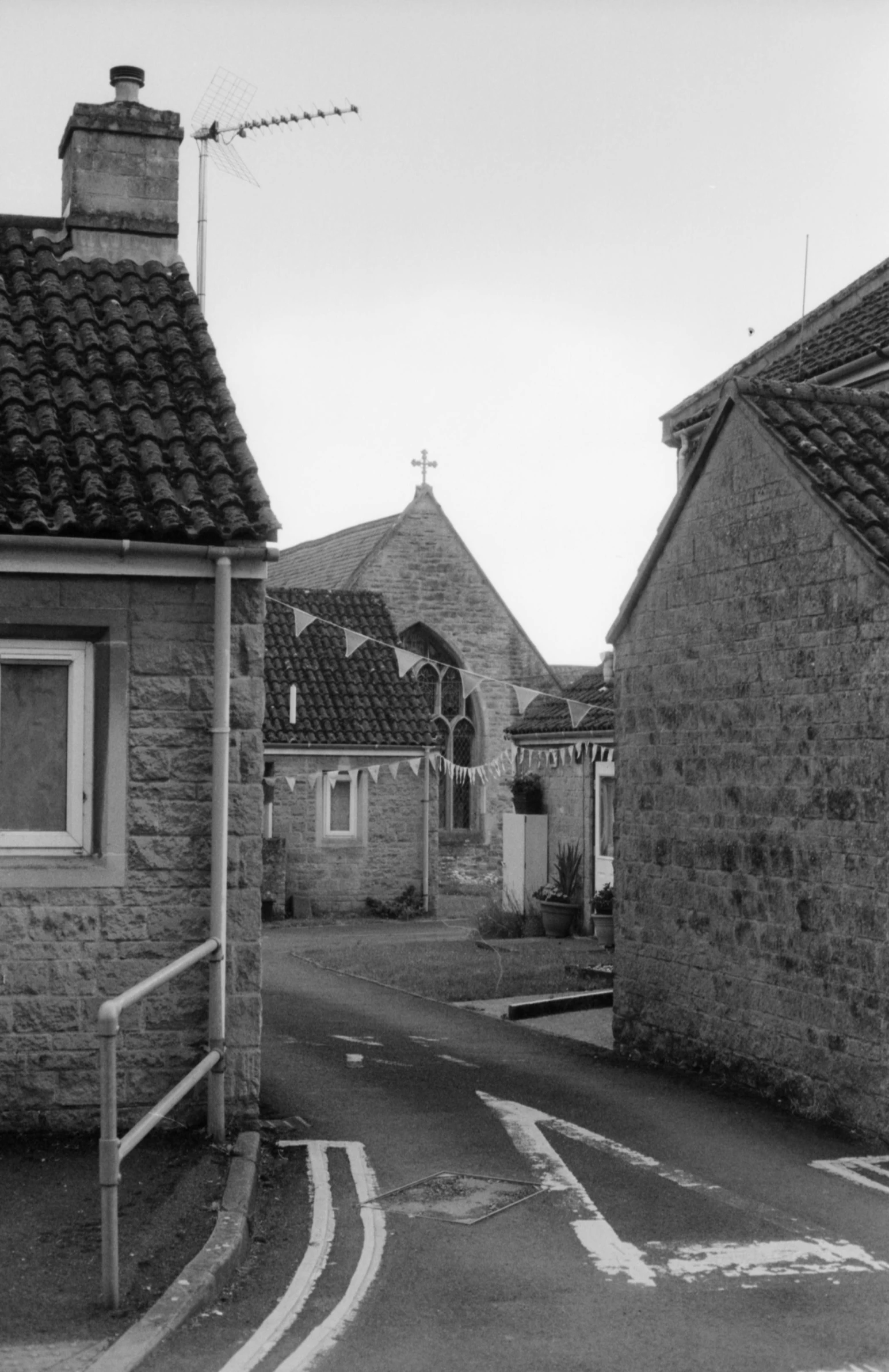 a black and white photo of a narrow street, a black and white photo, inspired by Bert Hardy, unsplash, romanesque, red roofs, in dunwall, rounded roof, churches