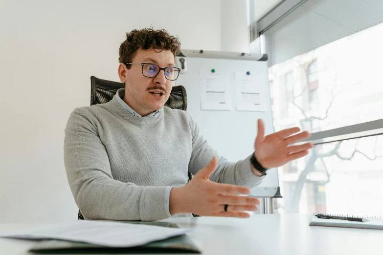 a man sitting at a desk in front of a computer, liam brazier, giving an interview, high quality photo, thumbnail