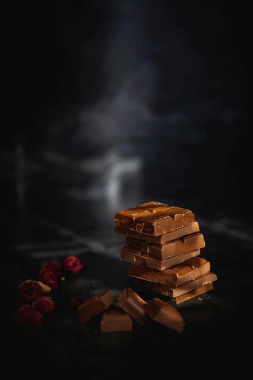 a stack of chocolates sitting on top of a table, inspired by Jules Robert Auguste, romanticism, spooky fog, caramel. rugged, in dark night, sultry