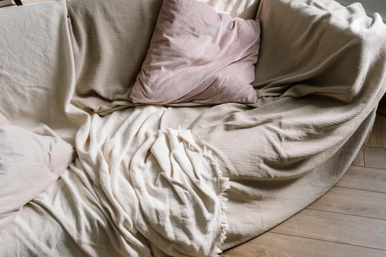 a white couch sitting on top of a hard wood floor, inspired by Aimé Barraud, featured on pinterest, baroque, curled up under the covers, faded pink, sandy beige, high angle