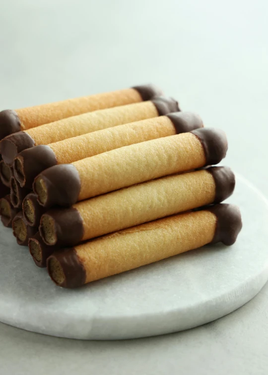 a stack of cookies sitting on top of a white plate, inspired by Okada Hanko, renaissance, cigars, chocolate sauce, 6 pack, tubes