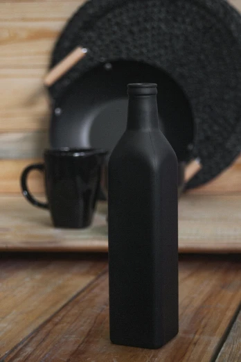 a black bottle sitting on top of a wooden table, pexels contest winner, all black matte product, ceramics, promo image, set photo