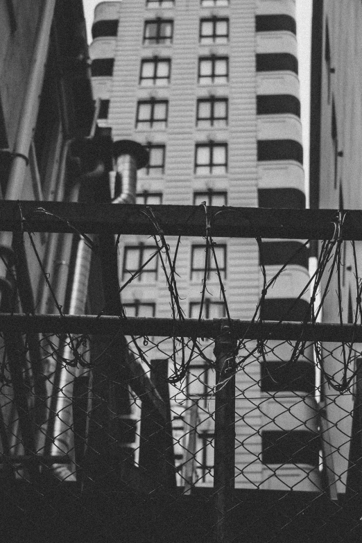 a black and white photo of a tall building, a black and white photo, unsplash, conceptual art, fences, 5 0 mm kodak, urban jungle, barbed wire