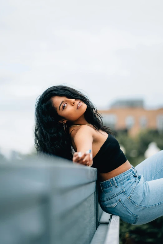 a woman in a black top and jeans leaning on a railing, by Niko Henrichon, trending on pexels, renaissance, lush black hair, wearing crop top, doing a majestic pose, portrait of vanessa morgan