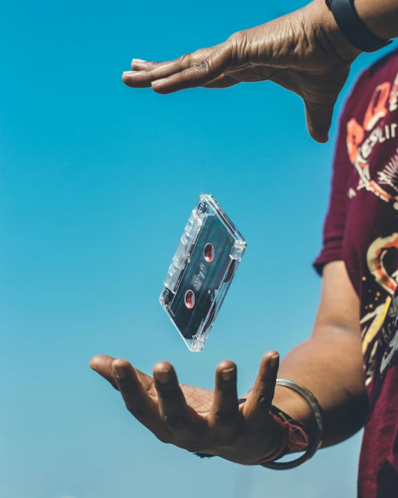 a man holding a cassette in his hand, an album cover, pexels contest winner, mid air, lgbtq, instagram story, cardistry