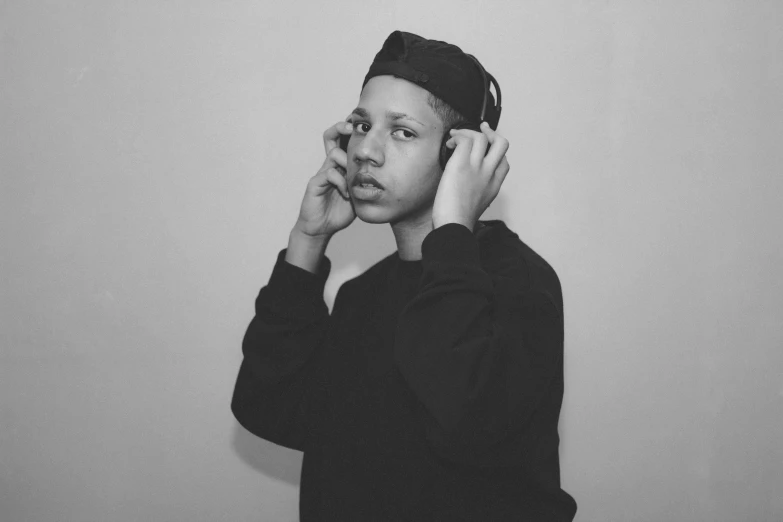 a black and white photo of a man talking on a cell phone, an album cover, unsplash, realism, without eyebrows, black teenage boy, headphones on head, portrait pose