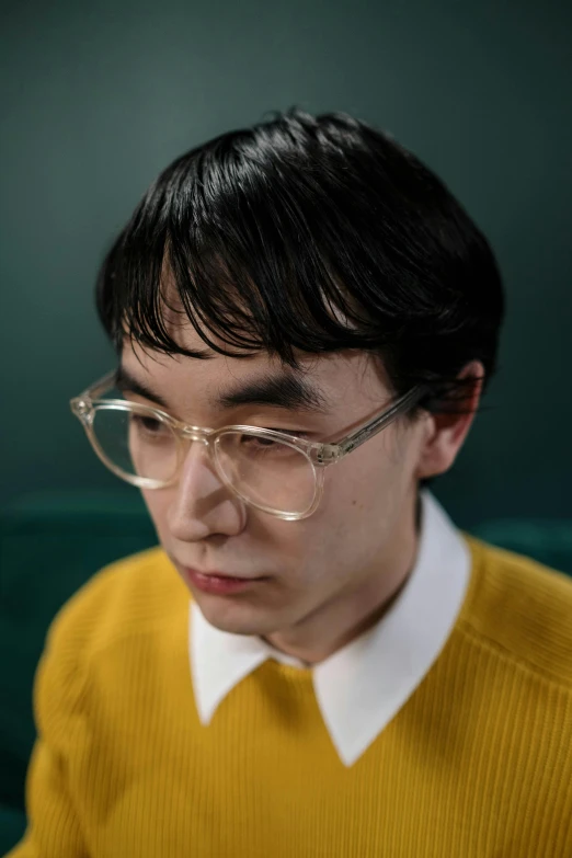 a man in a yellow sweater and glasses looking at a cell phone, an album cover, inspired by jeonseok lee, hyperrealism, medium close up portrait, pictured from the shoulders up, androgynous person, photographed for reuters
