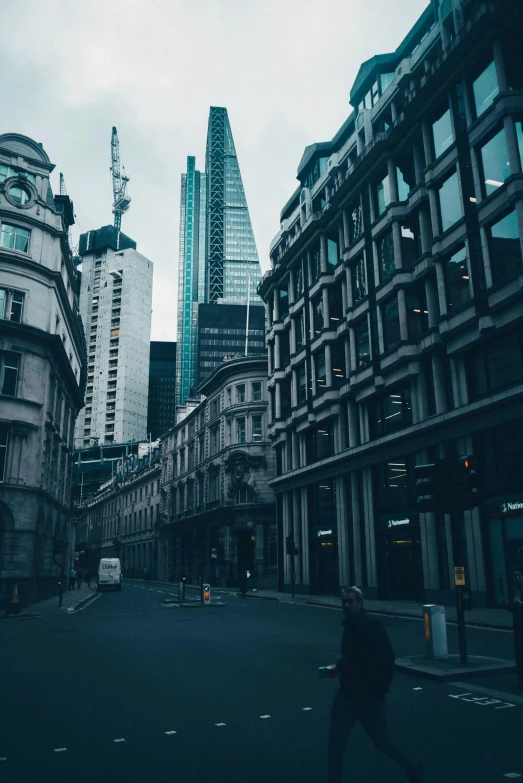 a person walking down a street next to tall buildings, pexels contest winner, england, buildings covered with greebles, gif, square