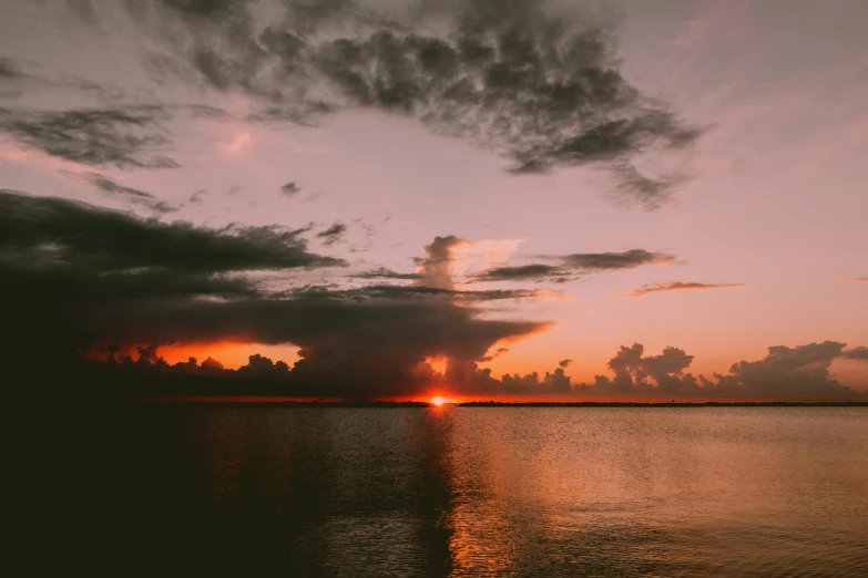 the sun is setting over a body of water, pexels contest winner, moody cloudy sky, crimson clouds, humid evening, multiple stories