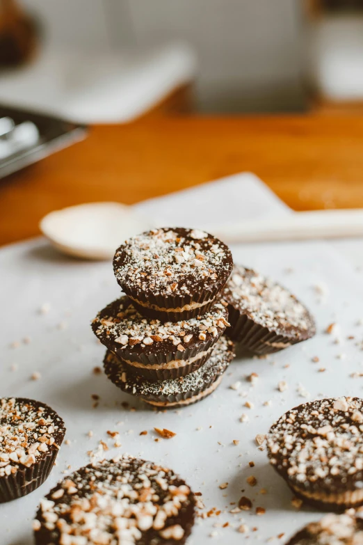 a table topped with chocolate cupcakes covered in powdered sugar, a portrait, unsplash, marshmallow graham cracker, thumbnail, natural morning light, parchment paper