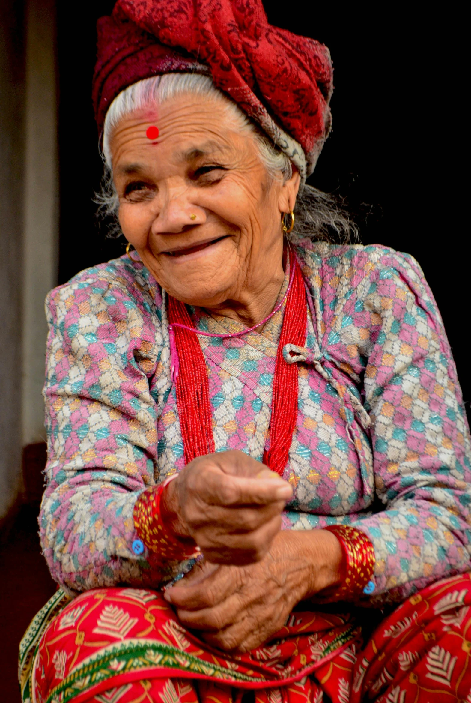 a woman that is sitting down with a smile on her face, by Dan Content, pexels contest winner, hurufiyya, nepal, smiling and dancing, lots of wrinkles, promo image