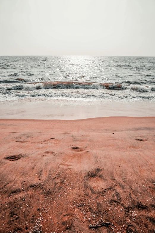 a sandy beach with footprints in the sand, an album cover, trending on unsplash, color field, sri lanka, faded pink, cover with a lot of red water, brown skin like soil