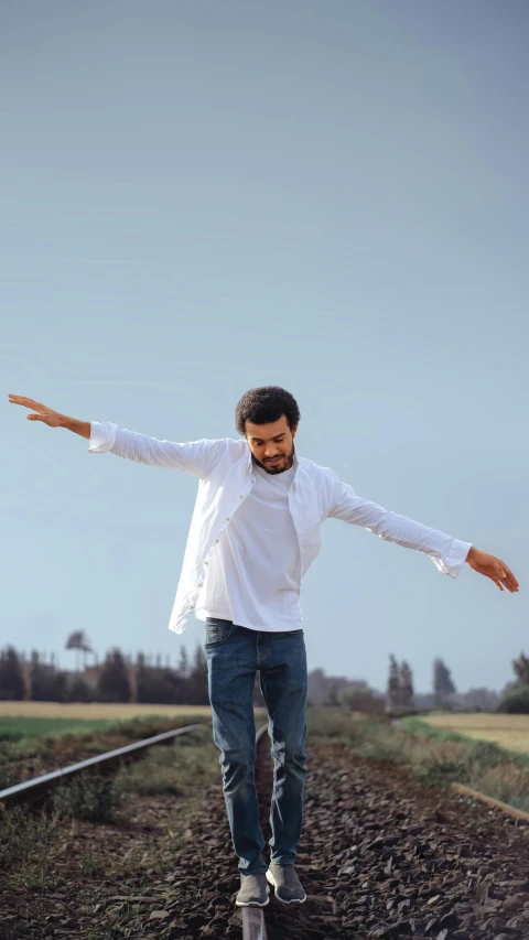 a man standing on a train track with his arms outstretched, by Ismail Acar, happening, white shirt and jeans, looking happy, 15081959 21121991 01012000 4k, on grey background