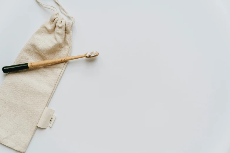 a toothbrush sitting on top of a bag next to a toothbrush, unsplash, minimalism, beige, bamboo, white, background image