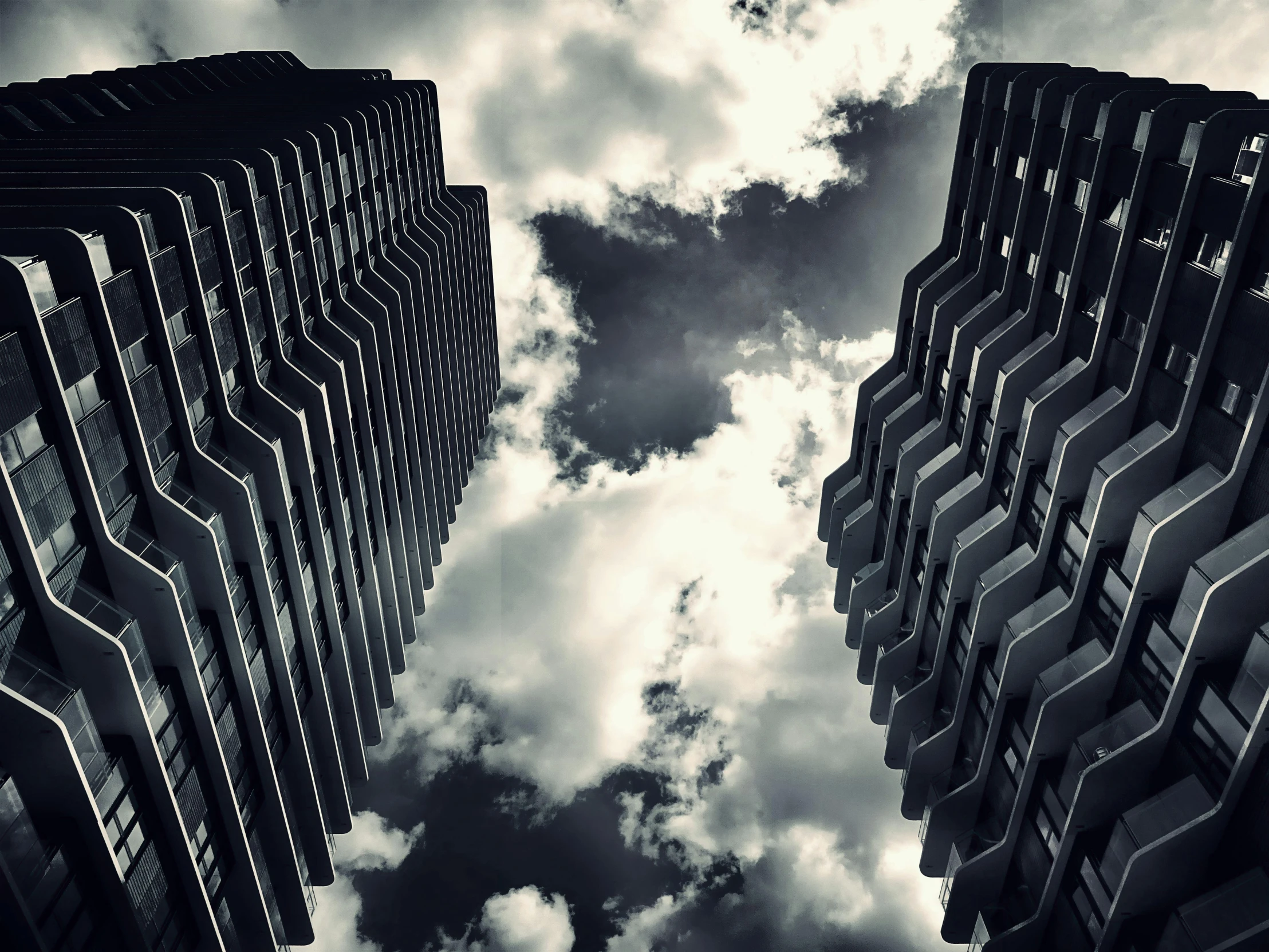 a couple of tall buildings sitting next to each other, by Adam Rex, pexels contest winner, brutalism, black clouds, vertigo, the sky is black