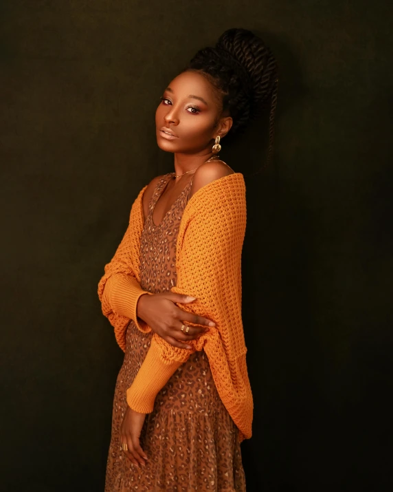 a woman standing in front of a black background, an album cover, inspired by Chinwe Chukwuogo-Roy, trending on pexels, renaissance, he is wearing a brown sweater, wearing a yellow dress, wearing a cardigan, orange hue