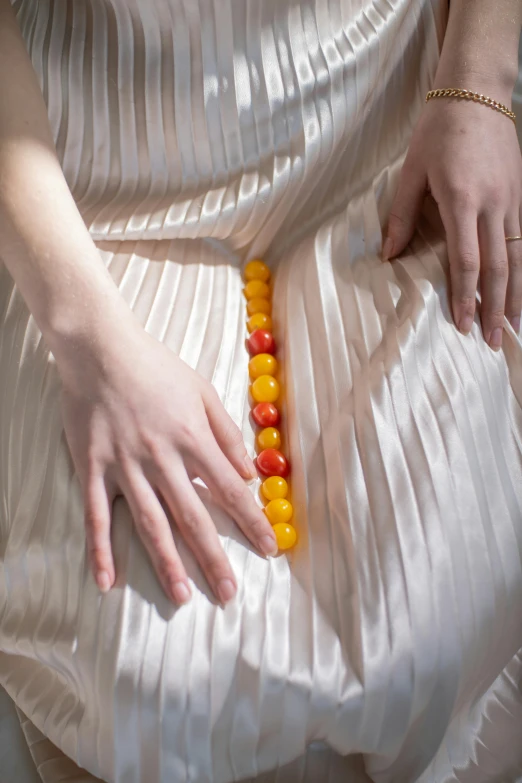 a woman in a white dress with a beaded belt, an album cover, inspired by Wilhelm Hammershøi, trending on reddit, made of candy and lollypops, detail shot, hands straight down, edible